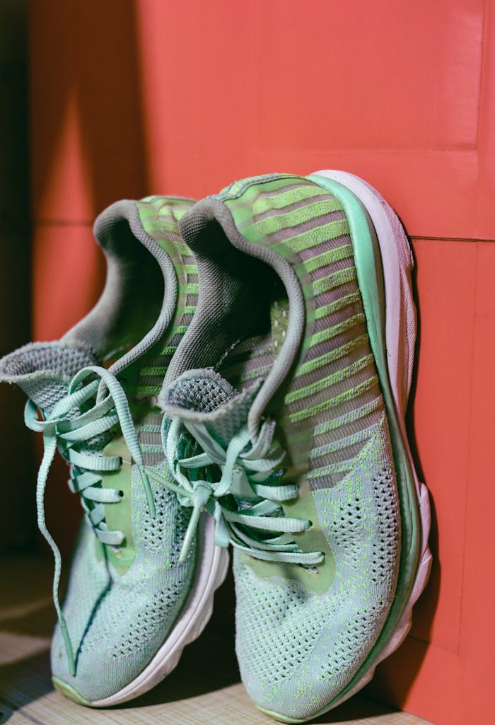 Close-up of green sneakers leaning against a vibrant red backdrop for a dynamic contrast.